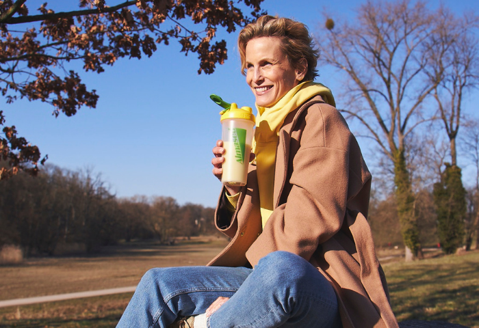 ältere Frau sitzt in der Natur mit einem Shake
