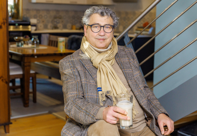 Mann sitzend in einer Wohnung mit einem Glas Almased in der Hand