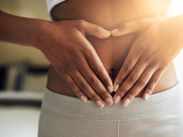 Frau macht Herzform vor dem Bauch