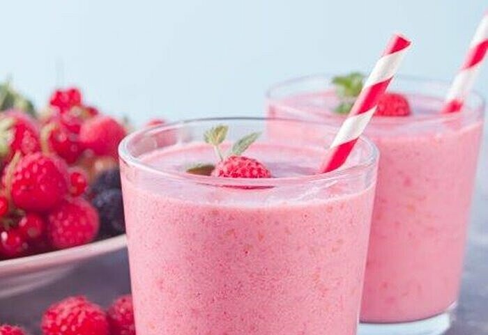 Rosa Abnehmshake mit Himbeeren in zwei Gläsern mit Strohhalm