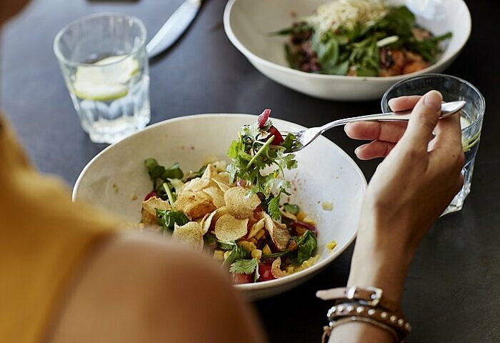 Frau-isst-proteinreichen-Salat-an-einem-Tisch-im-Restaurant