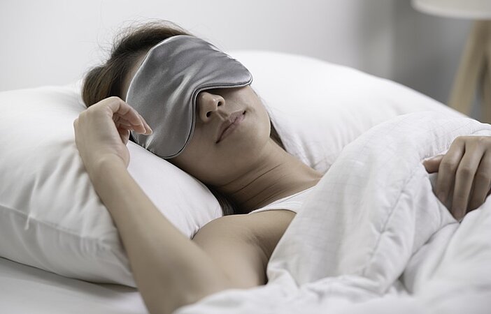 frau-mit-schlafmaske-im-bett-um-stoffwechsel-zu-optimieren