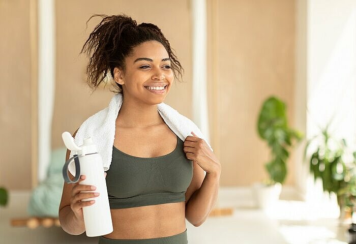 Protein-Shakes-sportliche-lächelnde-Frau-mit-Handtuch
